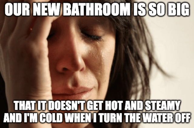 The meme features a close-up image of a person with dark hair, their hand resting on their forehead, conveying a frustrated or sad expression. Overlaid text at the top reads 'OUR NEW BATHROOM IS SO BIG' and continues at the bottom: 'THAT IT DOESN'T GET HOT AND STEAMY AND I'M COLD WHEN I TURN THE WATER OFF'. The humor stems from the relatable everyday frustration of a large bathroom lacking the warmth and steam retention of a smaller space, leading to discomfort after showering.
