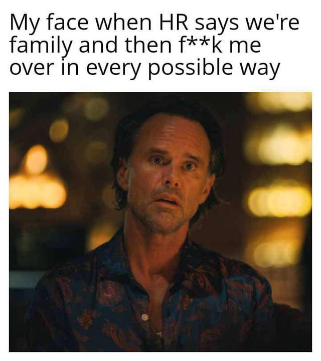 The meme features a top text overlay and a screenshot of a real man with a shocked, disbelieving facial expression. The text reads: 'My face when HR says we're family and then f**k me over in every possible way'. The background consists of blurred warm-toned lights, suggesting an indoor setting (e.g., a restaurant or bar). The man's wide eyes and open mouth convey surprise and disappointment, visually emphasizing the betrayal described in the text, where HR's 'family' rhetoric is followed by mistreatment.
