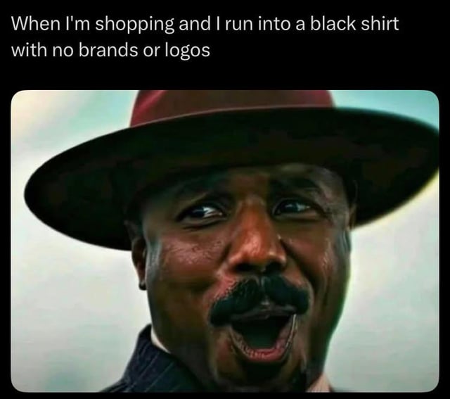 This is a relatable reaction meme. Top text reads 'When I'm shopping and I run into a black shirt with no brands or logos', paired with a close-up still of the character Bass Reeves from the series *Lawmen: Bass Reeves* making an extremely overjoyed, ecstatic expression. The joke plays on the common experience of people who prefer simple, unbranded minimalist clothing: finding a perfect plain black tee, a versatile staple wardrobe item, feels like an incredibly exciting win, which is exaggerated by the character's intensely happy reaction.