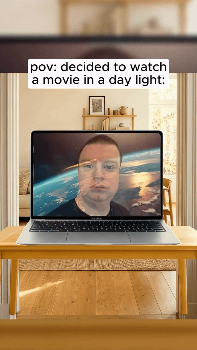This relatable meme depicts a laptop placed on a wooden table in a bright, sunlit residential living room. The laptop screen is supposed to display a space-themed movie, but heavy sunlight glare causes the face of the person watching the movie to be clearly reflected over the film content, making the movie nearly unwatchable. Text at the top of the image reads 'pov: decided to watch a movie in a day light:' to set up the scenario, joking about the common annoying experience of screen glare ruining daytime media viewing.