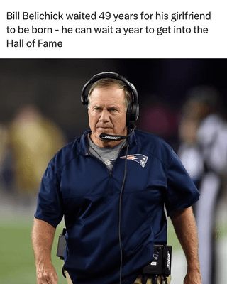 A meme featuring a photograph of Bill Belichick, a prominent NFL coach, standing on a football sideline. He is wearing a navy jacket with the New England Patriots logo, a headset, and has a serious, focused expression. The text overlay humorously contrasts his 49-year wait for his girlfriend's birth with the suggestion that waiting a year for Hall of Fame induction is trivial by comparison, emphasizing his patience.