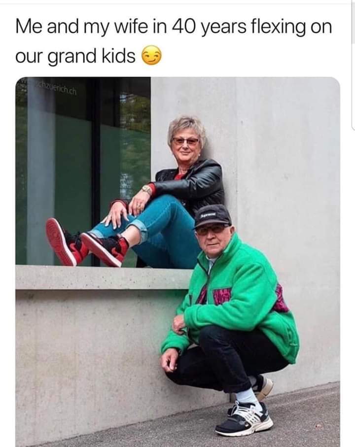 This wholesome meme uses a photograph of an elderly couple posing in casual, trendy streetwear to humorously imagine the user and their partner "flexing" (showing off a cool, youthful vibe) to their future grandchildren. The woman sits on a concrete window ledge wearing a black leather jacket, rolled jeans, and red sneakers, with a relaxed, amused expression. The man squats below her in a bright green fleece jacket, baseball cap, and stylish sneakers, looking directly at the camera. The caption above reads: *Me and my wife in 40 years flexing on our grand kids 😏*, playing on the relatable idea of staying young at heart and maintaining a fun, cool persona even in old age. It's a lighthearted, positive take on aging and future family dynamics.