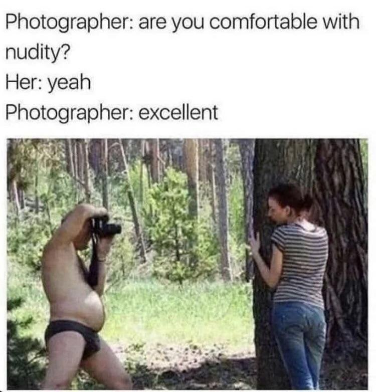 This meme uses a bait-and-switch joke to subvert audience expectations. The top text contains a conversation: a photographer asks a woman if she is comfortable with nudity for an outdoor photoshoot, she replies yes, the photographer responds 'excellent'. The photograph below reveals that the photographer himself is the one nude (wearing only a small black brief), while the woman remains fully clothed posing against a large tree in a forest. The joke plays on the audience's initial, common assumption that the woman would be the one nude for the shoot, flipping the expectation for awkward comedic effect.