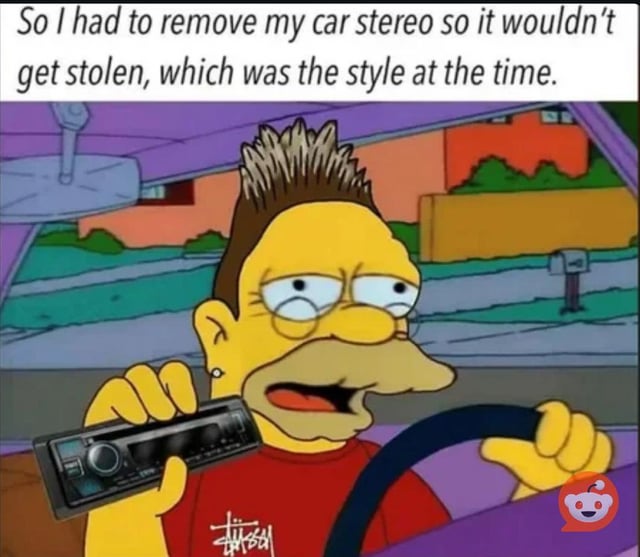 An animated meme featuring a spiky-haired character from The Simpsons driving a car. The character, wearing a red shirt, holds a car stereo in one hand while gripping the steering wheel with the other. The background shows a suburban neighborhood with colorful houses, trees, and a mailbox. At the top of the image, text reads: 'So I had to remove my car stereo so it wouldn’t get stolen, which was the style at the time.' The character has a tired, exasperated expression, enhancing the humorous and sarcastic tone that frames past theft-prevention measures as a 'style' trend.
