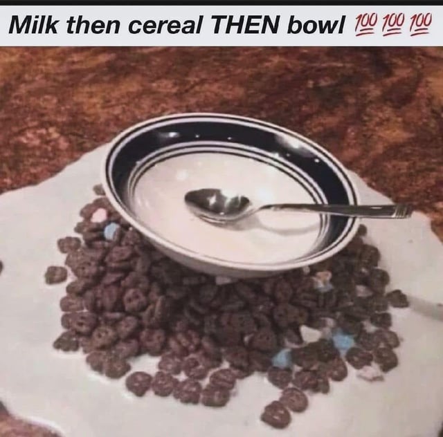 This meme is a joke responding to the popular long-running internet debate over the correct order to prepare cereal: pouring cereal first versus pouring milk first. The image displays an absurd setup: a bowl filled only with milk with a spoon inside is placed directly on top of a pile of dry cereal that is spilled across a paper towel laid on a kitchen countertop, with milk also visible leaking under the cereal onto the towel. The text at the top reads "Milk then cereal THEN bowl 💯💯💯", proposing a ridiculous, nonsensical third order of operations to "settle" the debate completely by leaning into absurdist humor.
