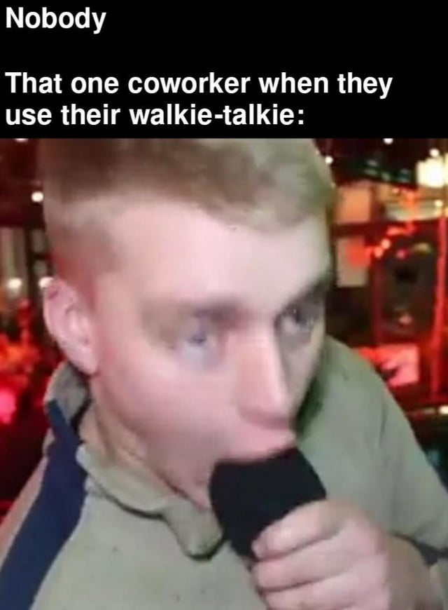 A meme consisting of two lines of text at the top and a photograph below. The top text reads 'Nobody' followed by 'That one coworker when they use their walkie-talkie:'. The photograph shows a real person with short blonde hair, wearing a light-colored shirt with a dark stripe, holding a black microphone/walkie-talkie close to their mouth. The background is a blurred indoor setting with warm red lighting, suggesting a bar, restaurant, or casual workplace. The humor stems from the relatable scenario of coworkers who speak excessively loudly into walkie-talkies, with the intense visual of the person emphasizing the over-the-top volume.