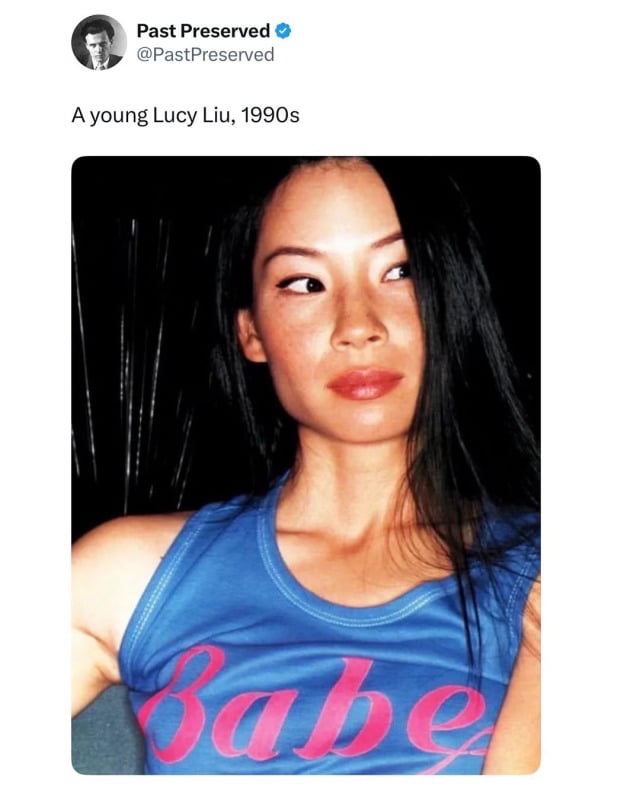 This image is a screenshot of a social media post containing a vintage photograph of famous American actress Lucy Liu taken in the 1990s. In the photo, young Lucy Liu has long straight black hair, wears a blue tank top printed with the word "Babe" in pink cursive font, looks off to her left with a calm, neutral expression, and is positioned against a dark background. The post above the photograph is from the verified X (formerly Twitter) account Past Preserved (@PastPreserved), with the text caption reading "A young Lucy Liu, 1990s".