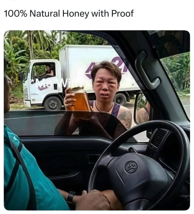 The image depicts a scene where a person inside a car is holding up a jar of honey, extending it towards another individual outside the vehicle. The top of the image features the text '100% Natural Honey with Proof'. In the background, there is a white truck with a purple '421' logo and partial text 'McM' visible, with a driver seated inside. The setting appears to be an outdoor area with greenery, including palm trees. The humor in the image stems from the sarcastic implication that simply holding the jar serves as 'proof' of the honey's natural quality, which is an exaggerated and unconvincing form of evidence.