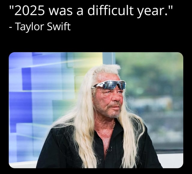 A meme consisting of a top text caption that reads, "2025 was a difficult year." attributed to Taylor Swift, paired with a photograph of Duane Chapman (known as Dog the Bounty Hunter), a real person with long white hair, wearing silver sunglasses and a black shirt, seated in a studio environment with a blurred blue and green abstract background. The humor stems from the absurd misattribution of the quote to Taylor Swift, creating a comedic contrast between the text and the image of Duane Chapman.