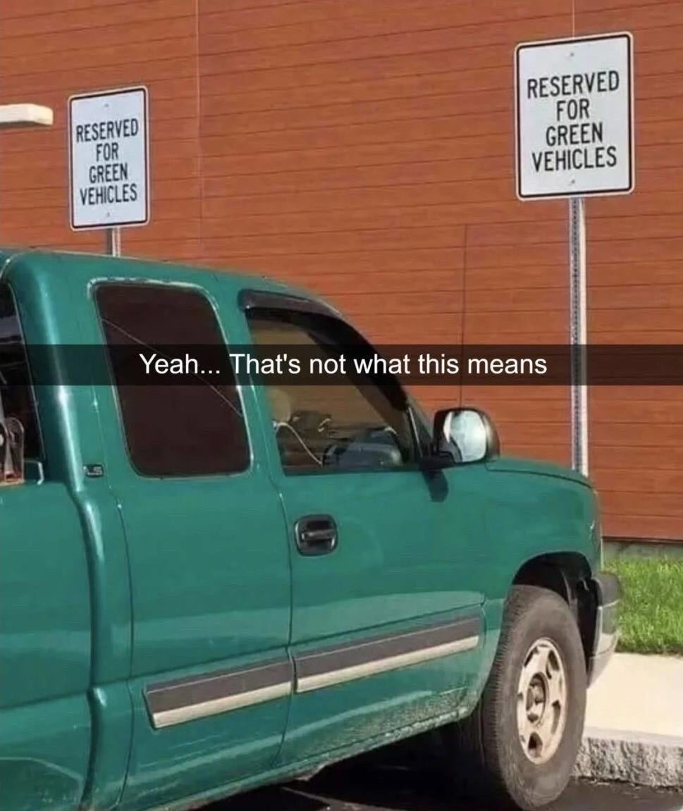 This meme features a dark green pickup truck parked in a space marked by two signs that state "RESERVED FOR GREEN VEHICLES". A text overlay across the center of the image reads "Yeah... That's not what this means". The core joke comes from a clear misinterpretation of the sign: the term "green vehicles" officially refers to eco-friendly, low-emission or energy-efficient vehicles such as electric or hybrid cars, but the driver of the green-colored truck appears to have incorrectly understood the sign to mean any vehicle with a green paint job, resulting in an ironic and humorous parking scenario.
