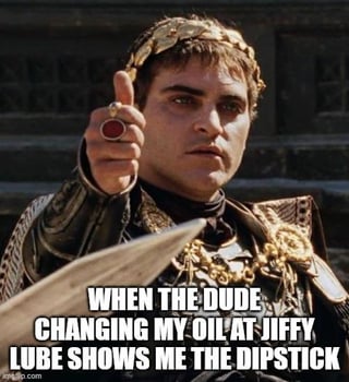 This meme uses a still of Joaquin Phoenix as Roman emperor Commodus from the 2000 film *Gladiator*, where the character gives a thumbs up gesture that in the original film signals approval of a gladiator's death. The overlaid text on the image reads "WHEN THE DUDE CHANGING MY OIL AT JIFFY LUBE SHOWS ME THE DIPSTICK", paired with the original Reddit post title "I'm not ordering $300 champagne, my guy". The joke humorously exaggerates the mundane car maintenance experience, mocking the common practice of Jiffy Lube employees trying to upsell unnecessary, overpriced add-on services to customers, framing the upsell pitch as absurdly formal, like being offered luxury champagne at a high-end restaurant, with the imperial thumbs up acting as sarcastic approval of the bold upsell attempt even as the poster refuses to pay for overpriced services.