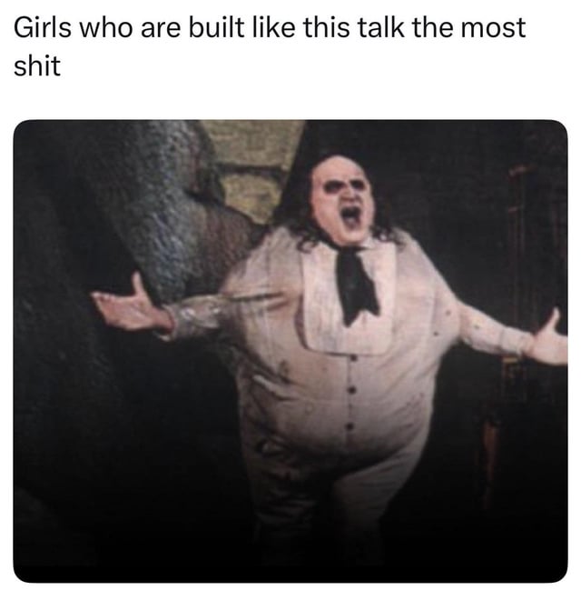 The meme consists of two parts: text at the very top reads 'Girls who are built like this talk the most shit', positioned above a still image of the Penguin character from the 1992 film Batman Returns. The character is a large, heavyset man with long dark hair, wearing a dusty light-colored formal suit and black necktie, yelling angrily with his mouth wide open, both arms outstretched to his sides palms up in a dramatic, argumentative pose. The humor of the meme comes from matching the character's loud, angry, large appearance to the stereotype that women with a similar body type are excessively loud, prone to gossiping, and frequently make rude or inflammatory comments.
