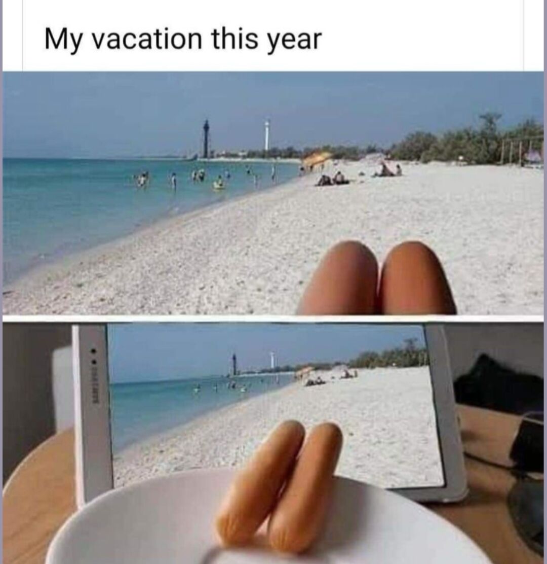 This is a two-panel visual joke meme. The top panel is captioned 'My vacation this year', and appears to show a first-person view of someone relaxing on a beautiful white sand beach with clear blue ocean, lighthouses, and other beach visitors in the background, with their two tanned knees in the foreground. The bottom panel reveals the trick: the beach scene is just an image displayed on a tablet screen, and the 'knees' are actually two small sausages placed on a white plate in front of the tablet, using forced perspective to create the illusion that the creator is actually on a beach vacation when they are at home. The joke is relatable for people who cannot take a real vacation and instead fake the experience for fun or social media.