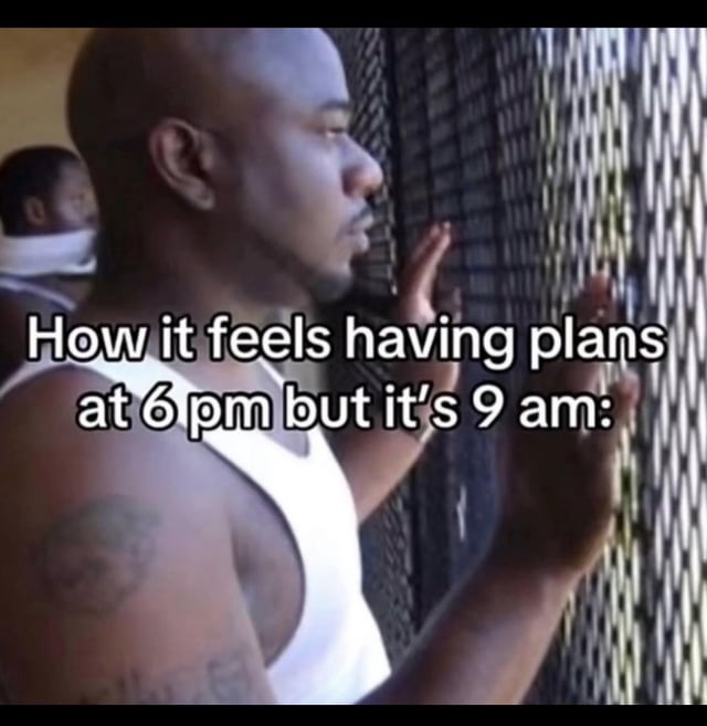 The meme features a still from a popular viral clip of a Black man in a white tank top pressing both hands against a metal mesh fence and looking outward longingly, as if waiting to be let out. Overlaid text on the image reads 'How it feels having plans at 6 pm but it's 9 am:'. The joke is relatable to anyone who has fun plans scheduled for later in the day, and feels bored, trapped, and impatient while waiting for the work or school day to pass so they can go to their planned activity.