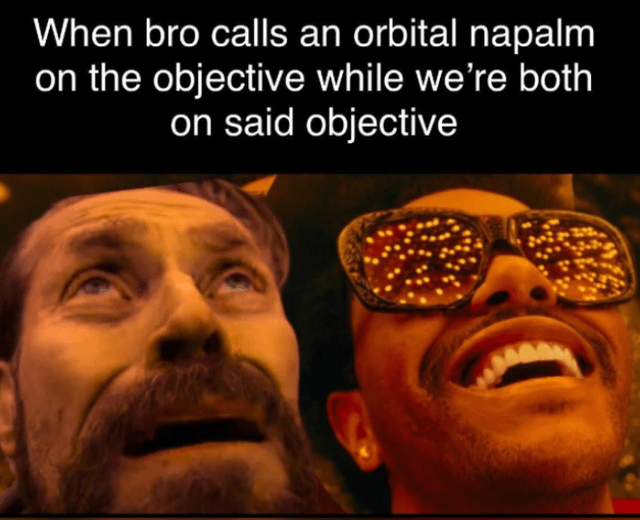 A meme in the gaming theme, specifically targeting FPS (First-Person Shooter) players. The top text reads: 'When bro calls an orbital napalm on the objective while we’re both on said objective'. Below the text is a screenshot from a live-action scene featuring two men. The left man has a beard, wide eyes, and an open mouth, appearing shocked as he looks upwards. The right man wears glasses with a pattern of small lights, laughing heartily with his head tilted back. The orange lighting suggests a dramatic or intense environment, humorously contrasting with the chaotic gaming scenario described in the text—depicting the relatable frustration and absurdity of a friend accidentally calling a destructive in-game strike on their own position.