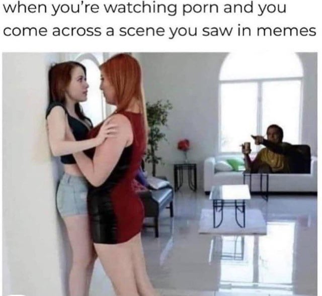 This meme features a top text caption: *"when you're watching porn and you come across a scene you saw in memes"*. The visual depicts two women in a suggestive, intimate embrace pressed against a wall in a modern living room. In the background, a man sits on a white couch holding a drink, pointing towards the pair with an amused, recognizing expression. The core humor comes from the relatable experience for frequent internet users: encountering a scene from adult content that has been widely circulated as a meme, breaking the immersion of the original content with the familiarity of the meme reference. The man's reaction mirrors the viewer's own sudden realization that they've seen this exact moment shared in meme form online, creating a funny contrast between the adult context and the casual, meme-aware response.