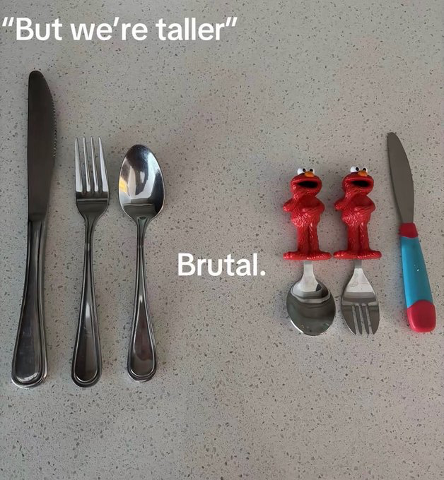 The image displays two groups of cutlery arranged on a light grey, speckled countertop. On the left are three standard, full-sized adult silverware pieces: a knife, fork, and spoon, with white text above them reading "But we're taller". On the right are three pieces of children's cutlery: a spoon and fork with red Elmo figurine handles (making the total height of these utensils taller than the adult silverware), plus a small knife with a blue and red handle. White text between the two groups reads "Brutal.". The humorous joke plays on technicality: the adult cutlery brags about being taller, but the children's cutlery are technically taller overall due to their decorative Elmo handles, even though their functional metal utensil ends are much smaller, making the adult silverware's brag fall flat.