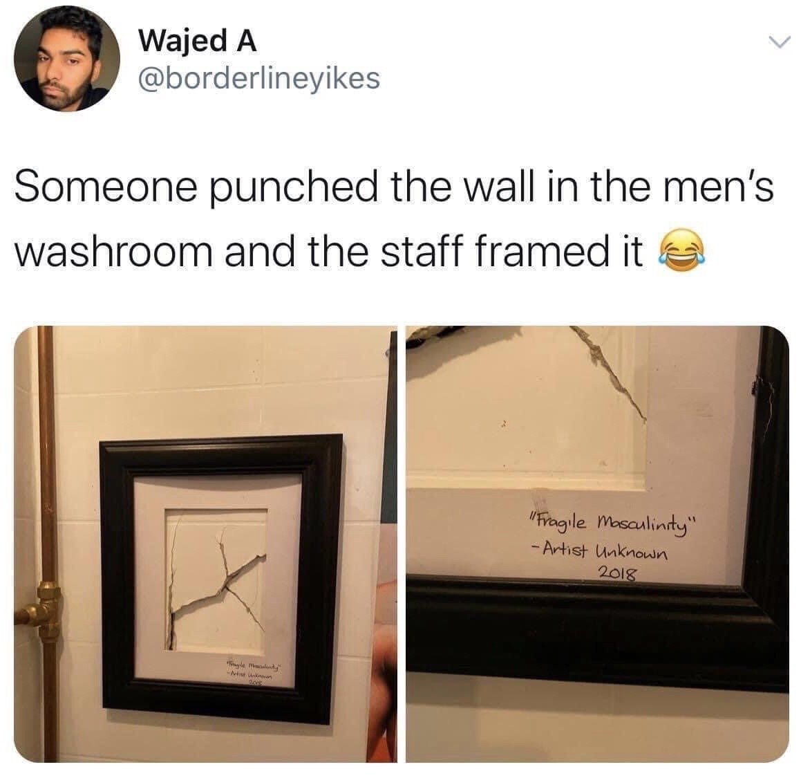 This is a screenshot of an X (formerly Twitter) post. The top of the screenshot shows the poster's profile picture, name Wajed A, and handle @borderlineyikes, followed by their post text: 'Someone punched the wall in the men's washroom and the staff framed it' paired with a laughing crying emoji. Below are two photos: the first shows a hole left by a punch in a tiled men's washroom wall, mounted inside a black picture frame as if it is a fine art piece. The second is a close-up of handwritten text on the matte of the frame, which reads: "Fragile Masculinity" - Artist Unknown 2018. The meme satirizes unnecessary aggressive outbursts associated with toxic masculinity by framing the vandalism as a comedic, intentional work of art.