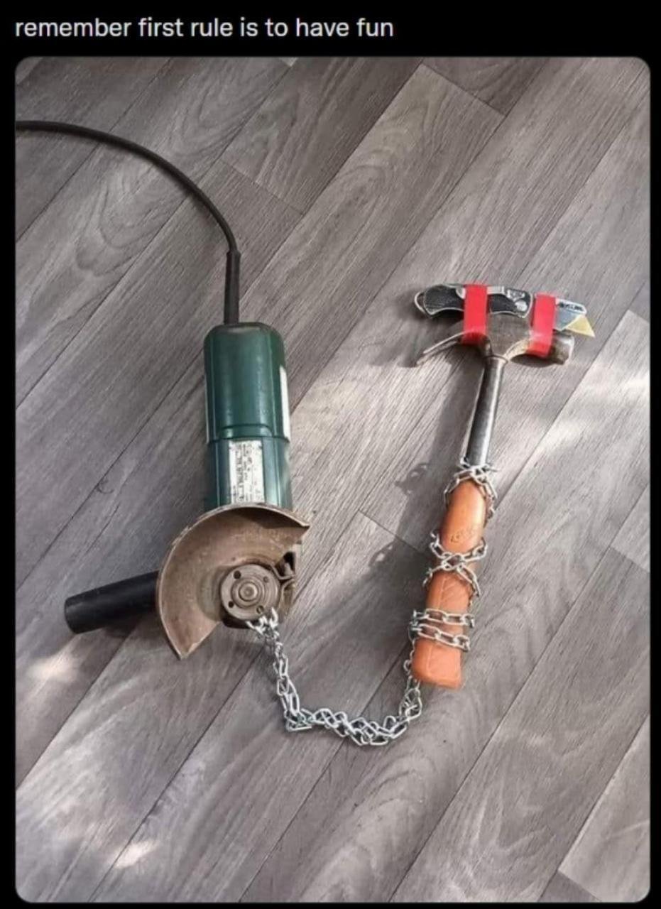 A photograph showing a green angle grinder with a black power cord and a hammer with a wooden handle and red attachments, both chained together with a metal chain, placed on a gray wooden floor. At the top of the image, there is a prominent text overlay that reads 'remember first rule is to have fun', creating a humorous contrast between the over-the-top secured tools and the lighthearted message.