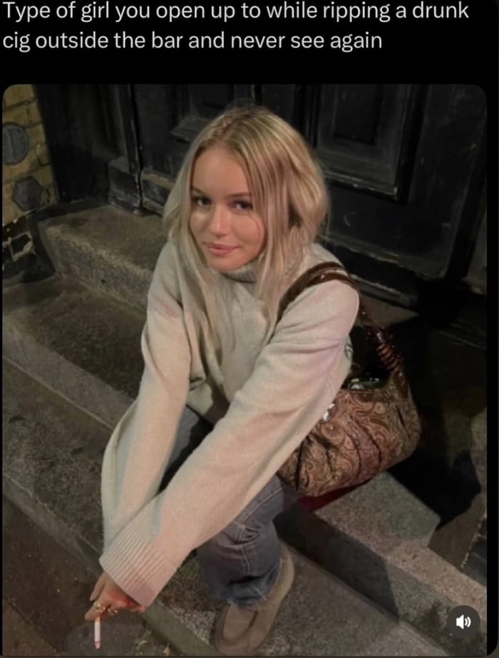 A photograph of a young woman with blonde hair, wearing a beige oversized sweater and blue jeans, sitting on stone steps outside a building at night. She has a brown patterned handbag beside her and is holding a cigarette in her right hand. The text overlay above the image reads: 'Type of girl you open up to while ripping a drunk cig outside the bar and never see again,' capturing the relatable experience of fleeting, intimate conversations with strangers in casual nightlife settings.
