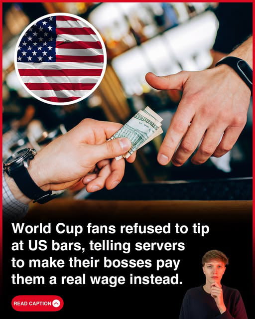 The meme features a circular icon of the United States flag in the top left corner. The central visual shows one hand holding a stack of US dollar bills offering a tip, while a second hand rejects the tip with a gesturing motion. At the bottom of the image, large white text states that World Cup fans visiting bars in the US refused to leave tips for service staff, instead telling servers to ask their employers to pay them a fair living wage rather than relying on customer tips. A small cutout of a young man with a thoughtful, pensive expression appears in the bottom right corner, and a red 'READ CAPTION' call-to-action button is placed in the bottom left. The meme comments critically on the widespread cultural expectation of tipping in the US service industry, which many argue is used to justify paying service workers below a living wage.