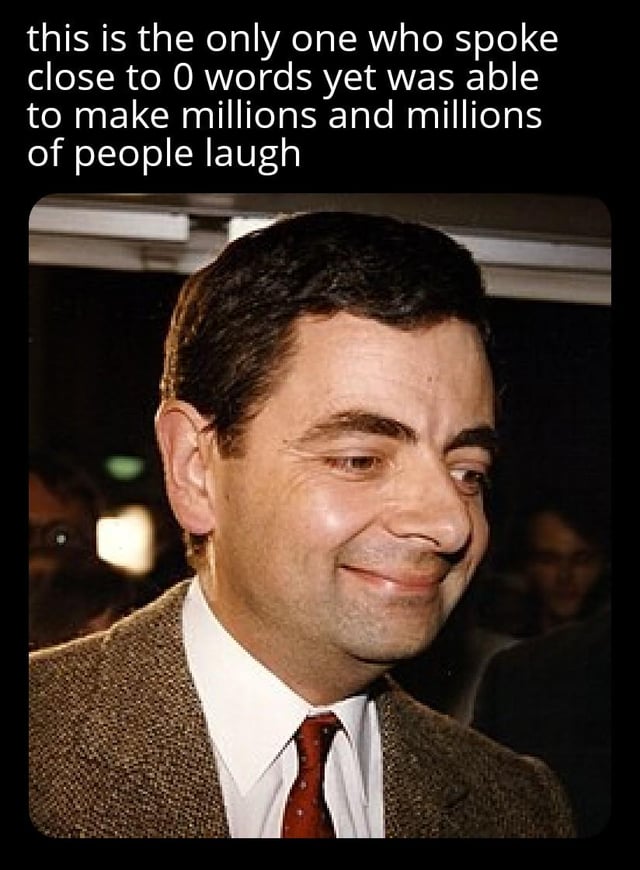 The image features a photograph of Rowan Atkinson, known for his role as Mr. Bean, smiling gently while looking to his right. He is wearing a brown tweed jacket, white shirt, and red tie. Above the photograph, there is a text overlay that reads: 'this is the only one who spoke close to 0 words yet was able to make millions and millions of people laugh'. The background of the photo is slightly blurred, suggesting a public event or gathering with indistinct figures in the distance.