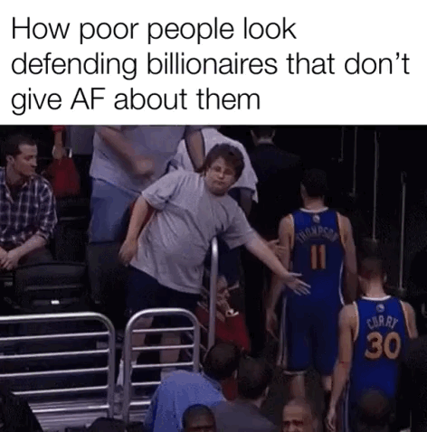 The meme consists of two parts: top text that reads "How poor people look defending billionaires that don't give AF about them", paired with a viral photo taken at an NBA game. In the photo, a male fan leans over stadium seating railings, extending his hand to high five Golden State Warriors players Klay Thompson (wearing jersey #11) and Stephen Curry (wearing jersey #30) as they walk off the court. Both players ignore the fan entirely, leaving his high five hanging unreturned. The visual is used as a sarcastic analogy for working class people who vocally defend ultra-wealthy billionaires, who in turn have no awareness of or investment in the wellbeing of those people.