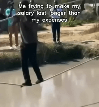 This is a relatable meme that uses a photo of a man precariously balancing on an extremely thin tightrope stretched across a large gap, to visually represent the difficult struggle of stretching a monthly salary to cover all monthly expenses. The text overlay compares the dangerous, high-stress balancing act to the common experience of trying to make income last when expenses are higher than your pay.