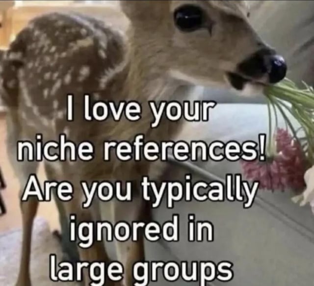 This meme features an image of a soft, spotted baby fawn holding a small bouquet of pink flowers in its mouth while looking directly at the viewer, giving an innocent, friendly impression. Overlaid white text first offers a warm compliment: 'I love your niche references!', then abruptly shifts to a personal, relatable question: 'Are you typically ignored in large groups', creating a humorous, unexpectedly relatable joke for people who often bring up obscure references that go unrecognized in bigger social settings.