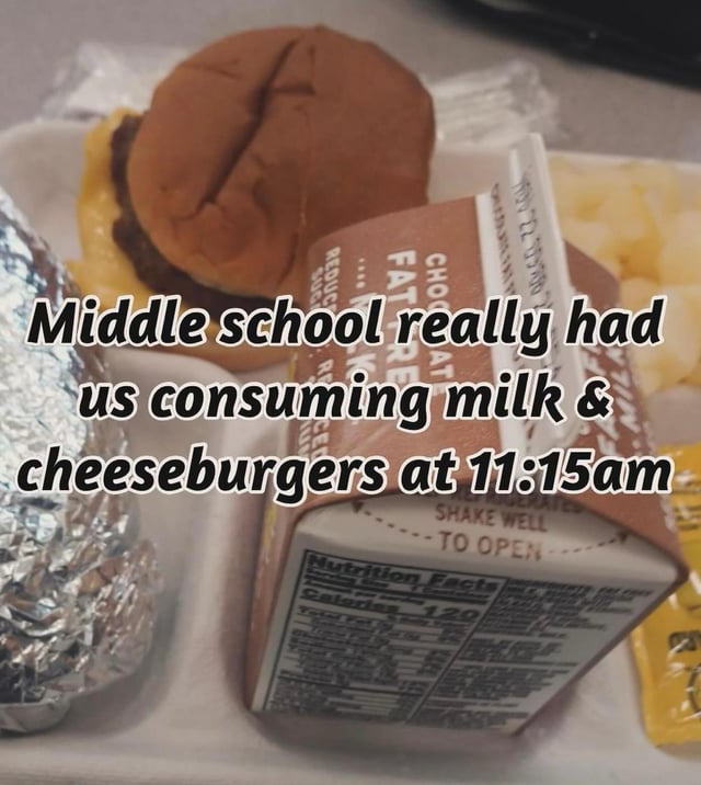 This is a relatable nostalgic meme showing a disposable school lunch tray holding a cheeseburger, a carton of chocolate fat-free milk, a wrapped food item, and side portions. The overlaid text comments on the notoriously early lunch times that many American students experienced during middle school, which is a widely shared, common memory.