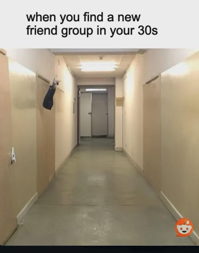 This is a relatable adulting humor meme. The visual shows a long, empty, plain institutional-style hallway with closed doors on both sides, fluorescent overhead lighting, and bare concrete flooring. The only non-building element is a single human arm extending out from a gap between two doors on the left wall, making a two-finger peace gesture while wearing a dark sleeve. The text printed at the top of the image reads "when you find a new friend group in your 30s". The joke relies on the common relatable experience that adults in their 30s often have limited free time and less opportunity to build new social connections, so finding even one new friendly person feels like joining a complete full friend group, represented by the nearly empty hallway containing only one partial person framed as an entire social group.