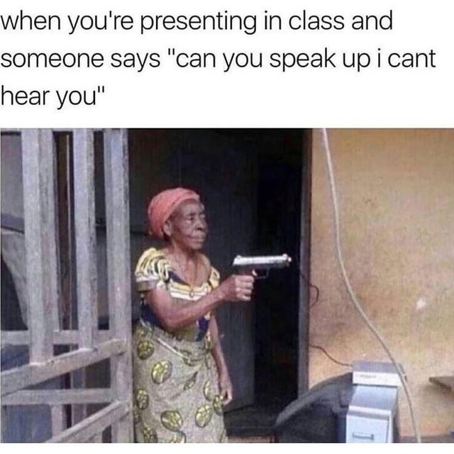 A meme featuring a top text overlay and a photograph. The text reads: 'when you're presenting in class and someone says "can you speak up i cant hear you"'. Below the text is a photograph of an older woman standing in a wooden doorway, wearing a colorful patterned dress and a red headscarf. She holds a silver handgun in her right hand, arms slightly extended, and looks to her left with a serious expression. The humor stems from the exaggerated, sarcastic reaction (brandishing a gun) to the common, mild classroom request to speak louder during a presentation.