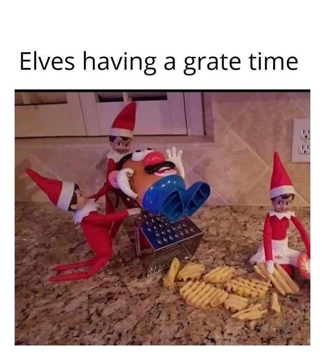 A humorous image featuring three Elf on the Shelf dolls interacting with a Mr. Potato Head toy on a kitchen counter. The elves are positioned around a metal grater; one elf appears to be pushing Mr. Potato Head's upper body into the grater, while another holds his legs, and the third sits nearby holding a small object. Scattered around the grater are various potato-shaped cutouts, mimicking grated potatoes. Above the image is the text 'Elves having a grate time,' which is a pun combining 'great' with 'grate' (referencing the kitchen tool).
