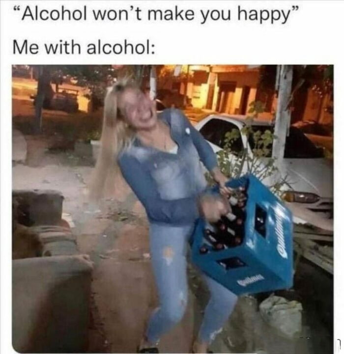 A meme featuring two lines of text and a photograph. The top text reads 'Alcohol won’t make you happy' followed by 'Me with alcohol:'. Below is a candid photo of a woman with long blonde hair, wearing a blue denim jacket and jeans, laughing loudly while carrying a blue Budweiser case filled with alcohol bottles. She is outdoors in an urban setting with parked cars and buildings in the background. The meme uses irony to humorously contradict the initial statement by showing the woman's obvious joy from having alcohol.