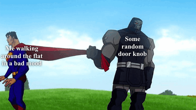 An animated meme featuring two characters from DC Comics. On the left, a character resembling Superman (blue suit, red cape) is labeled 'Me walking around the flat in a bad mood,' depicted walking with a neutral to slightly annoyed expression. On the right, a character resembling Darkseid (gray skin, black armor) is labeled 'Some random door knob,' standing sternly and holding onto Superman's cape, creating a humorous contrast between a person in a foul mood and an anthropomorphized, stubborn door knob. The background is a simple grassy field with a blue sky.