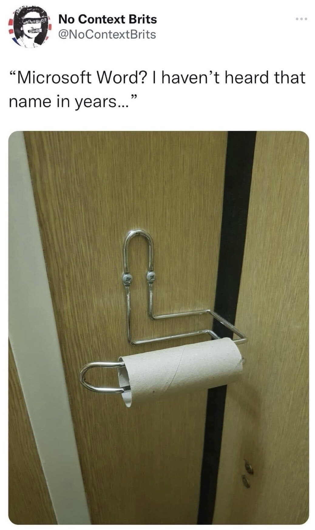 This meme is a screenshot of a post from the X (formerly Twitter) account @NoContextBrits. The post features a humorous quote: 'Microsoft Word? I haven't heard that name in years...' positioned above a photograph of a metal toilet paper holder mounted on a wooden bathroom stall door, which only holds an empty cardboard toilet paper core with no toilet paper remaining. The joke plays on the dual use of paper: paper used for printing documents created in Microsoft Word, and toilet paper. It references the 2020 COVID-19 pandemic toilet paper hoarding shortages, implying all available paper has been used up as toilet paper, so there is no paper left to use for printing documents from Microsoft Word, hence the speaker has not needed to use or hear about Microsoft Word in a long time.